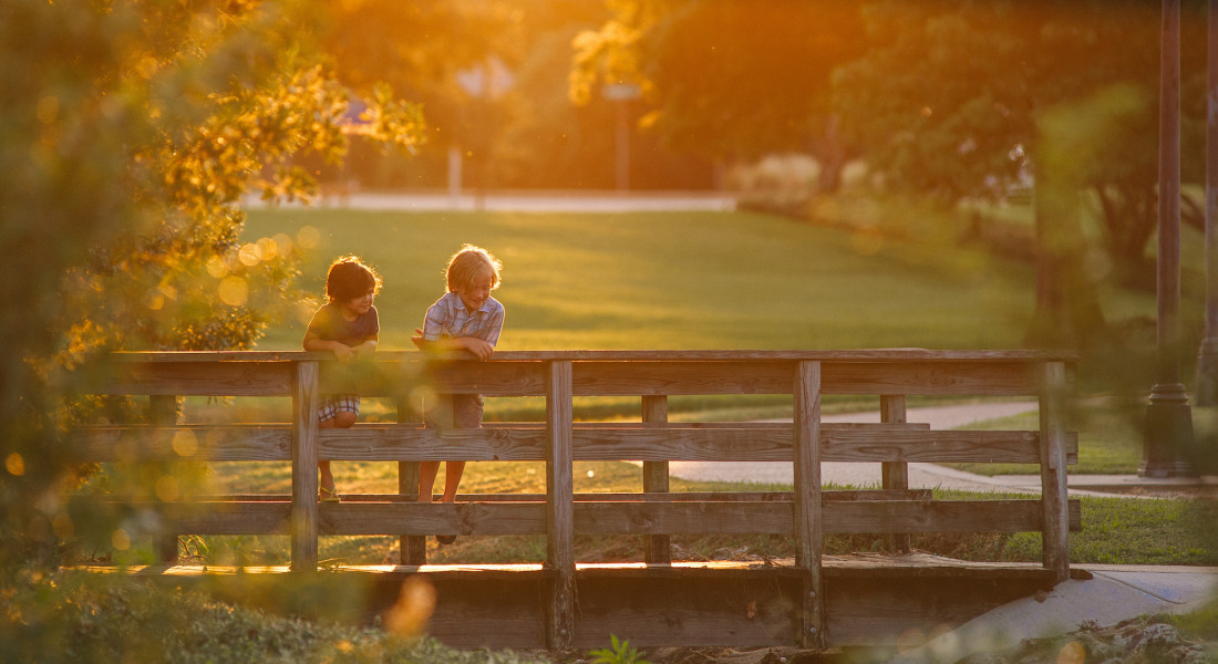 Two kids on a bridge with the sun setting in the background