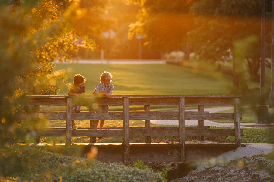 Two kids on a bridge with the sun setting in the background